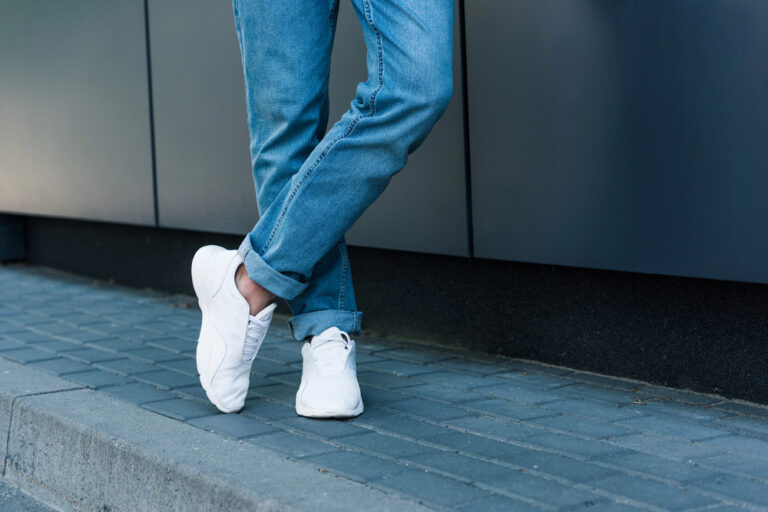 1 jeans, 3 looks: zo combineer je jouw heren jeans Man in jeans met witte sneakers op straat